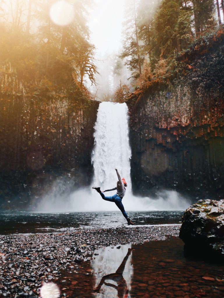 Person leaping at the foot of a waterfall